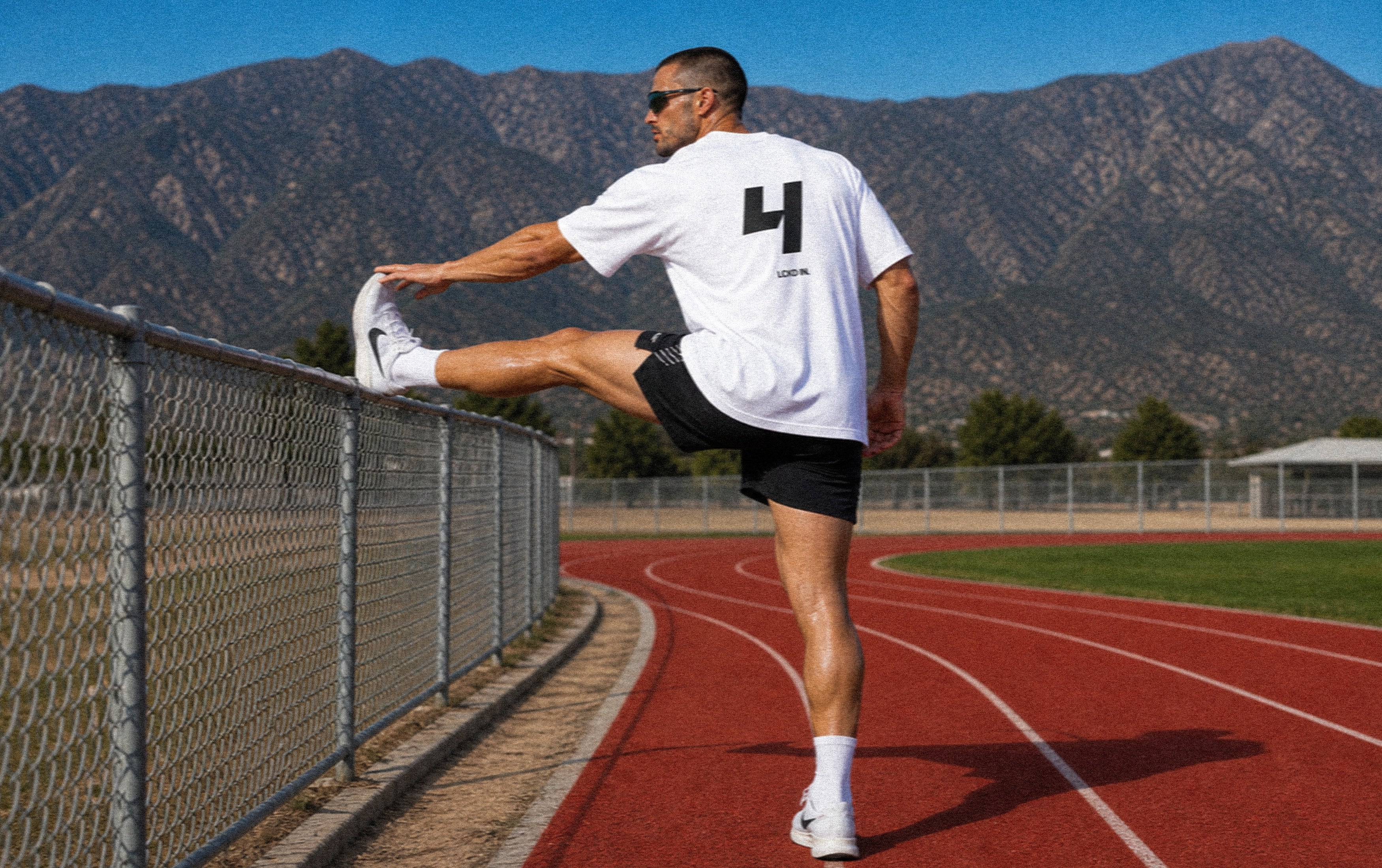 LCKD IN athlete in a white T-shirt stretching on a track