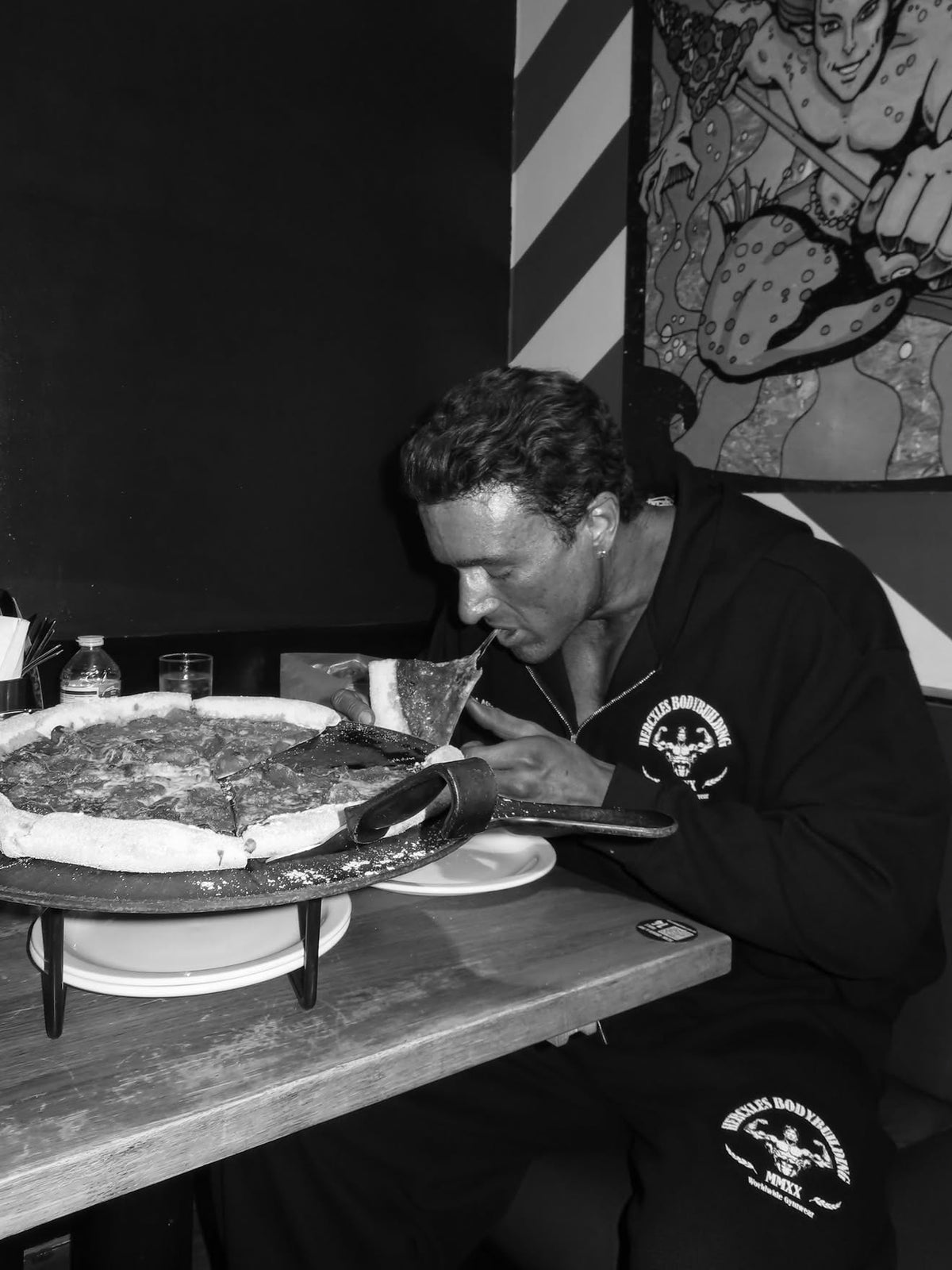 Worldwide Competitor Zip Hoodie - Black / White model seated in zip hoodie and matching joggers with pizza (p3)