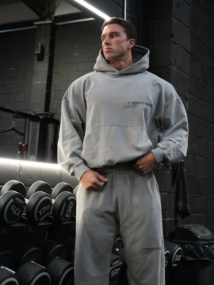 Athlete wearing the grey HERCSTUDIOS vintage boxy hoodie and sweatpants in the gym